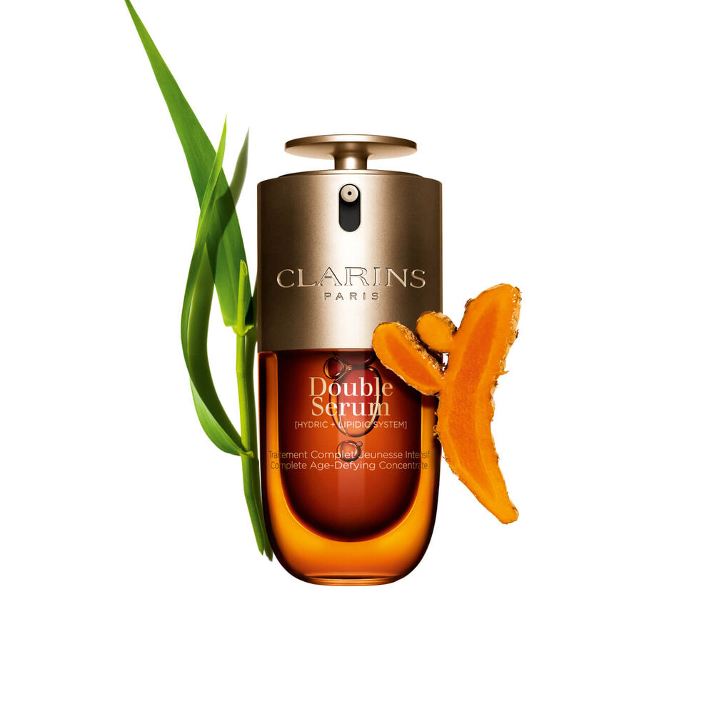 Packshot of the Clarins Double Serum displayed in front of its ingredient, including curcuma, on a gold background