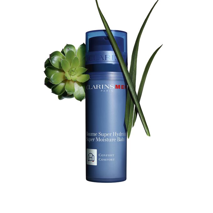 Packshot of a pump bottle of Clarins Men Super Moisture Balm close to gymnena and bison grass on a blue background.