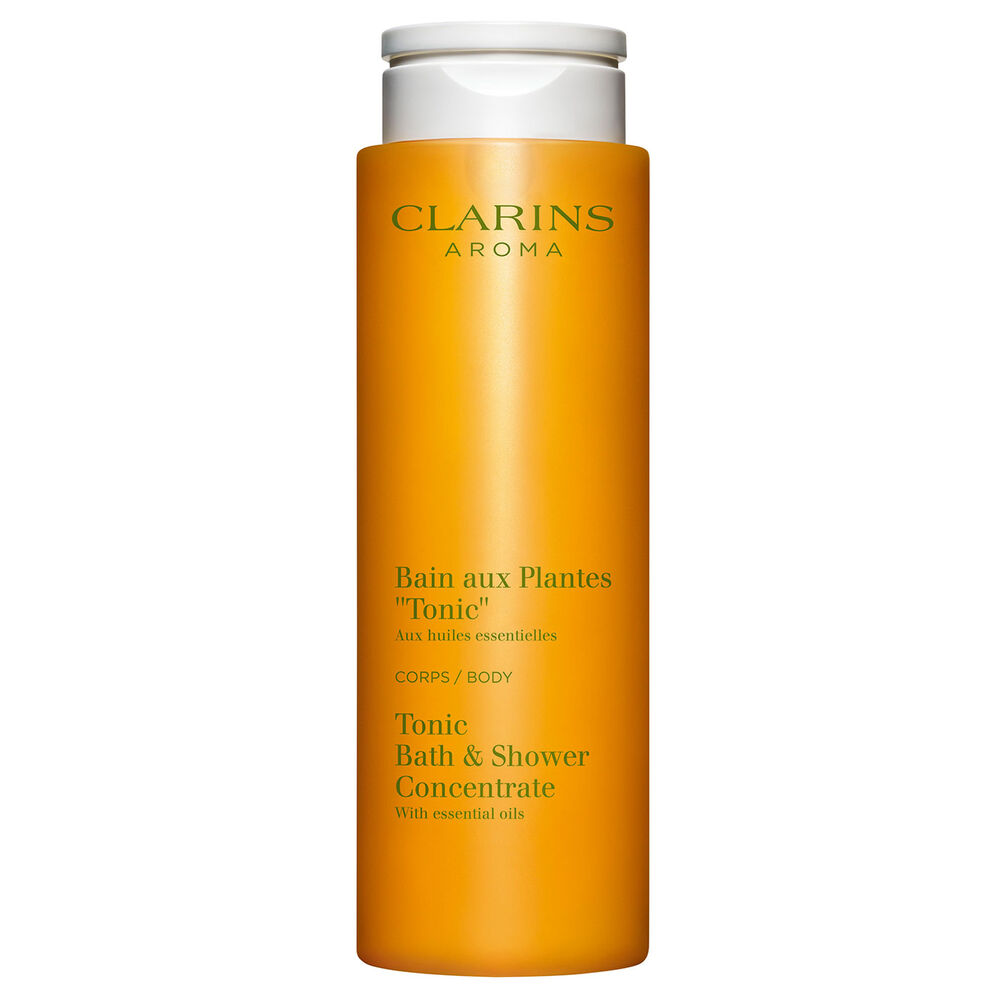 Packshot of Clarins Tonic Bath and Shower Concentrate gel, close to some mint and rosemary leaves on an orange background.