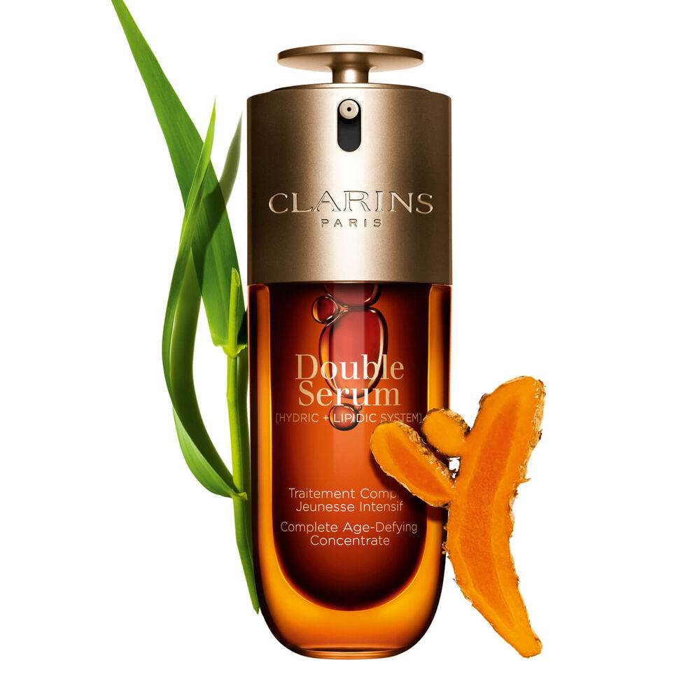Packshot of the Clarins Double Serum displayed in front of its ingredient, including curcuma, on a gold background
