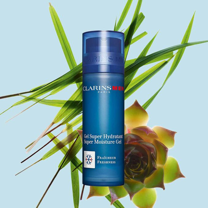 Packshot of a pump bottle of the Men Super Moisture Gel by Clarins close to gymnena and bison grass on a blue background.