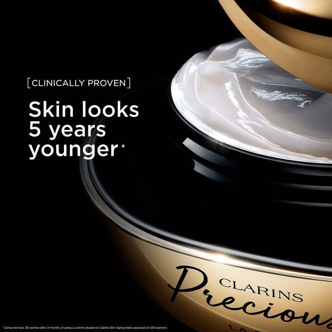 Packshot of Clarins Precious Soft Cream on dark background, with text emphasising its power to make skin appear 5 years younger.