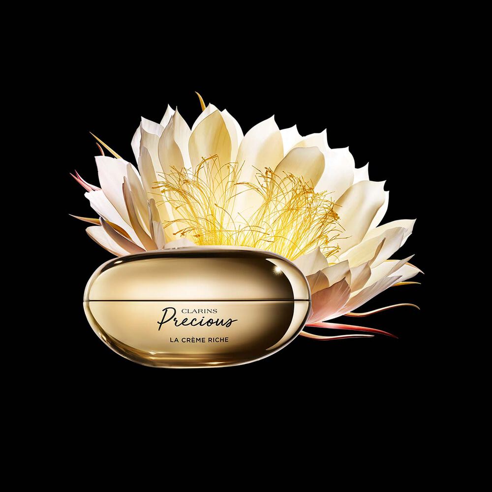 Packshot of Clarins Precious Rich Cream close to a Moonlight flower on dark background.
