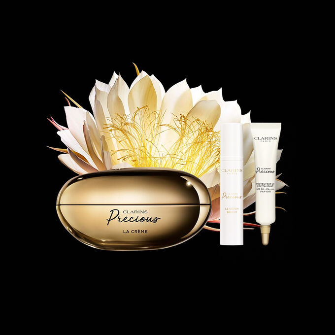 Packshot of Clarins Precious Soft Cream close to a Moonlight flower on dark background.