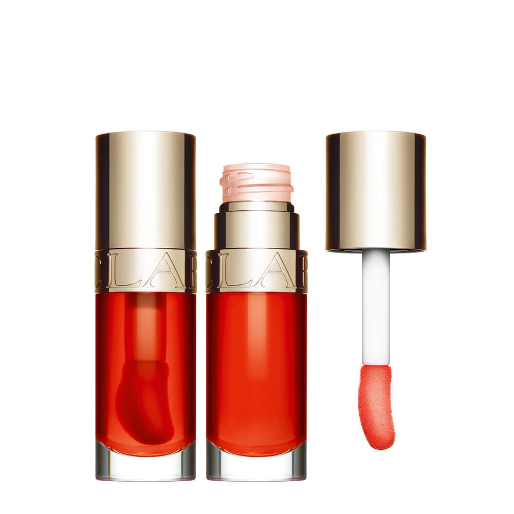 Packshot of Clarins Lip Comfort Oil Apricot, placed next to a sweetbriar rose on a light orange peach background.