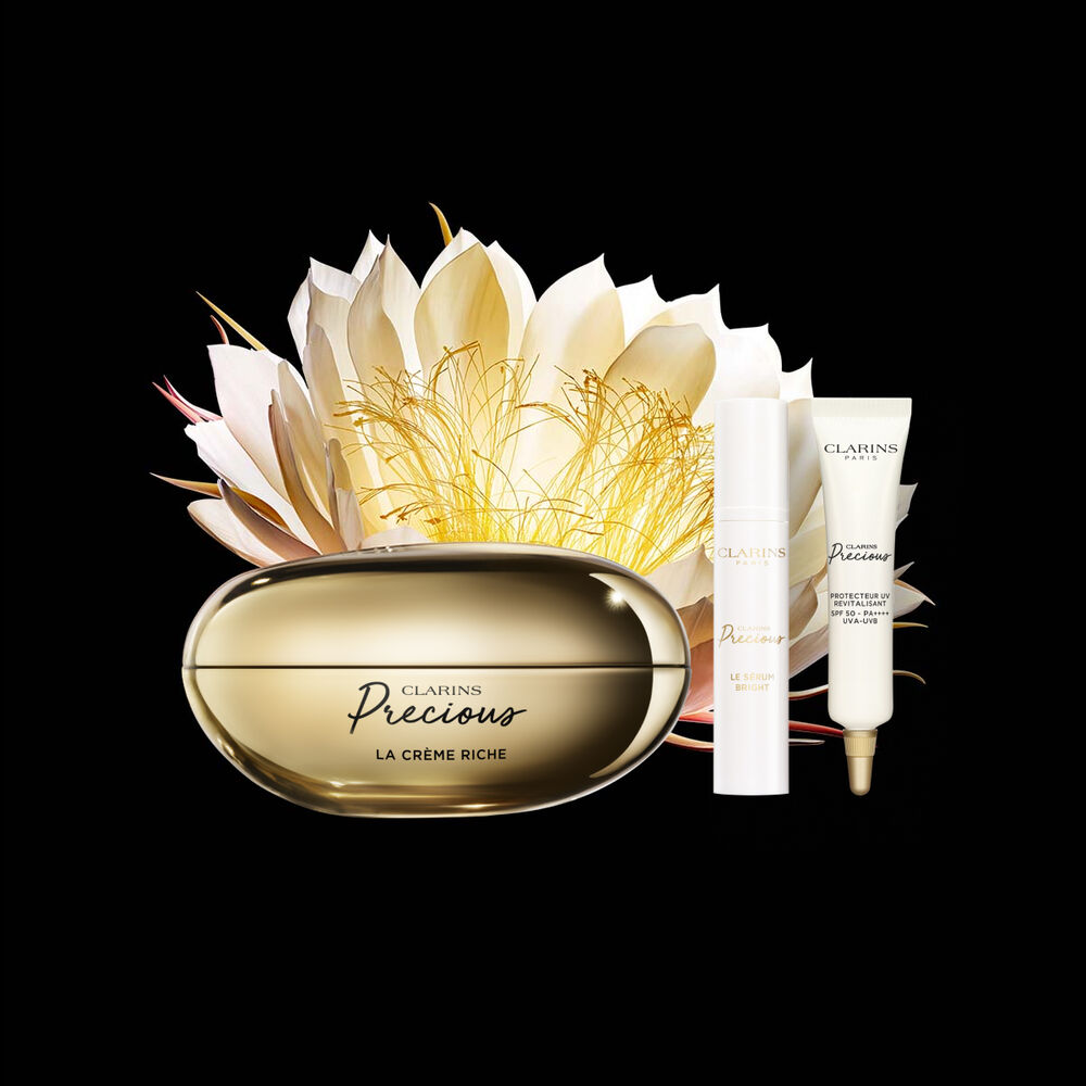 Packshot of Clarins Precious Rich Cream close to a Moonlight flower on dark background.