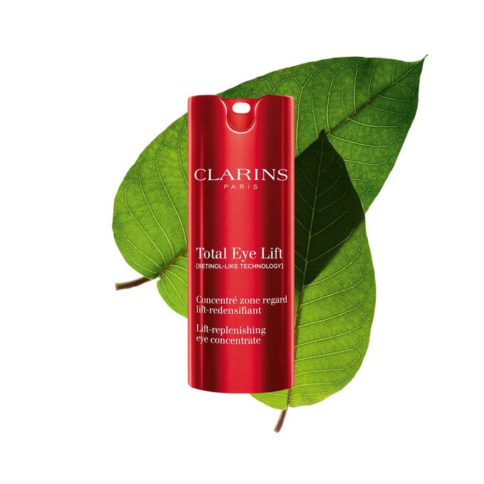 Packshot of Clarins Total Eye Lift anti-aging eye cream with harungana leaves on a dark red background.