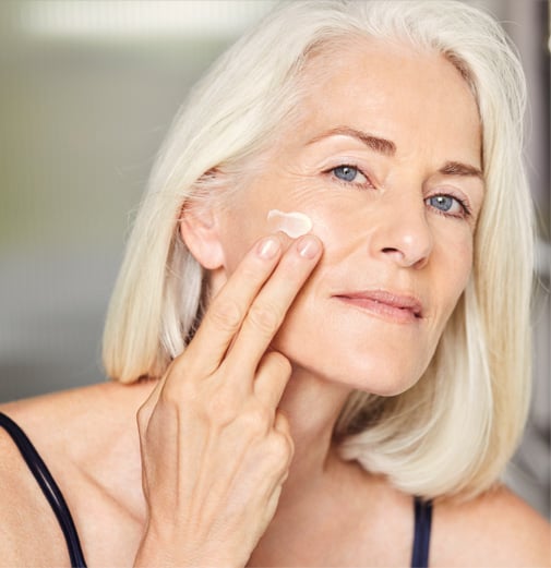 A mature women applying cream moisturiser on her face